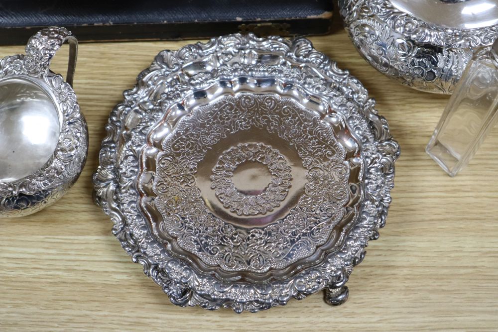 A cast and embossed silver plated teapot and matching milk jug, three plated card trays, etc.